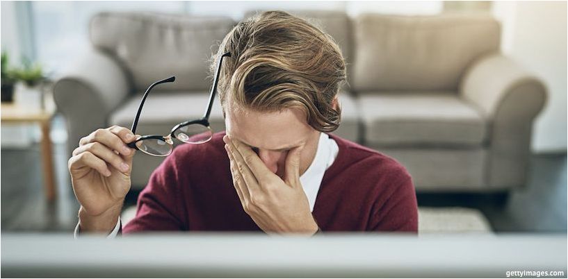 un homme se frotte les yeux devant un ordinateur