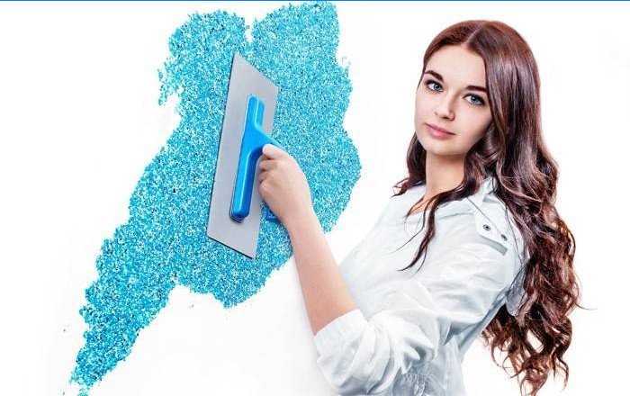 Fille met du papier peint liquide sur le mur