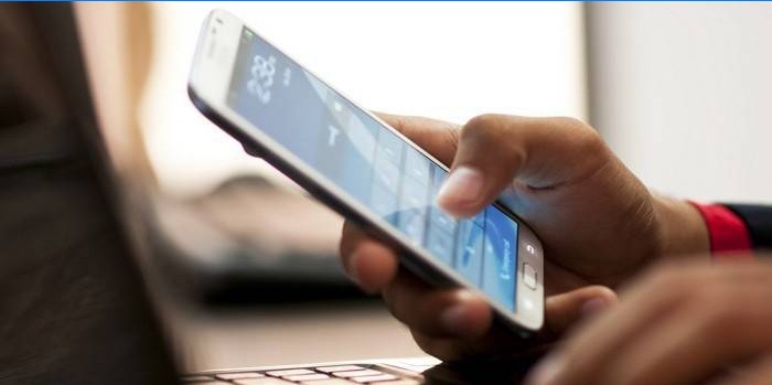 Le gars derrière l'ordinateur portable avec un smartphone à la main
