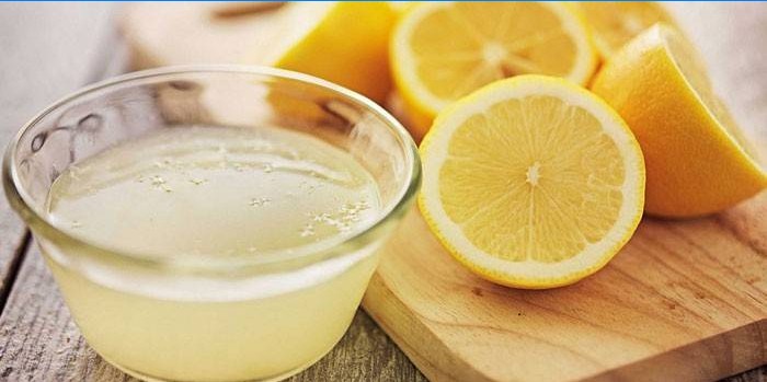 Jus de citron dans un bol et demi-citrons