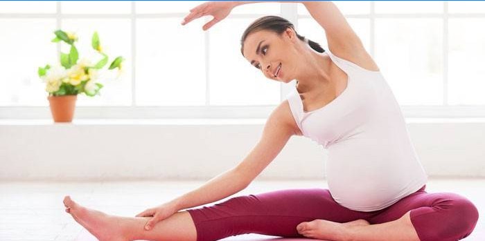 Une fille enceinte fait des exercices à la maison.