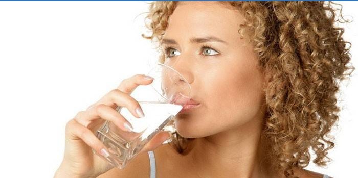 Fille boit de l'eau dans un verre