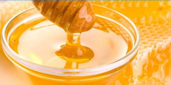 Miel dans un bol en verre et nid d'abeille