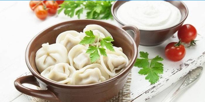 Dumplings bouillis dans une casserole et crème sure