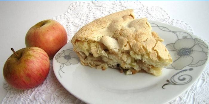Une tranche de tarte aux pommes sur une assiette et des pommes