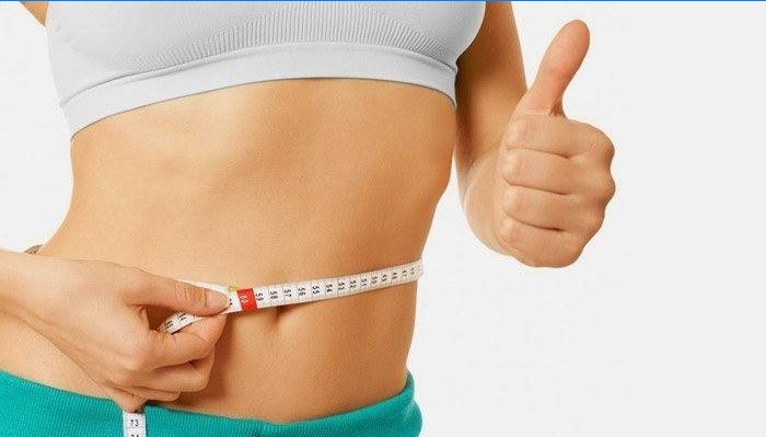 La fille mesure la taille après avoir perdu du poids