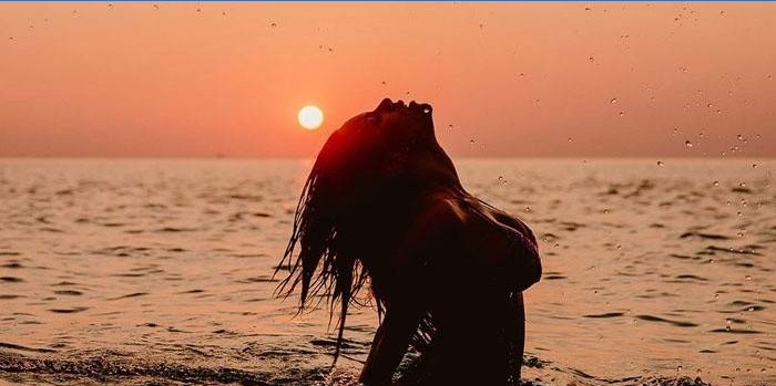 Fille dans la mer dans le contexte de l'aube