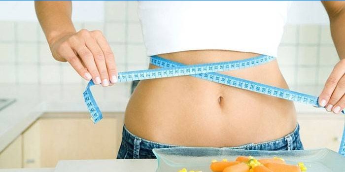 La fille mesure le volume de la taille avec un centimètre