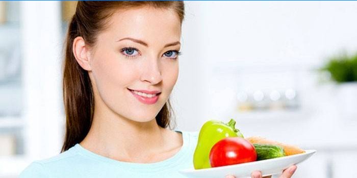 Fille tient une assiette avec des légumes à la main