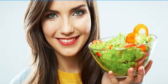 Fille tient une assiette avec salade à la main