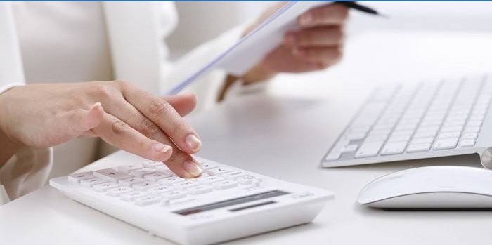 Fille avec une calculatrice, un ordinateur et des papiers