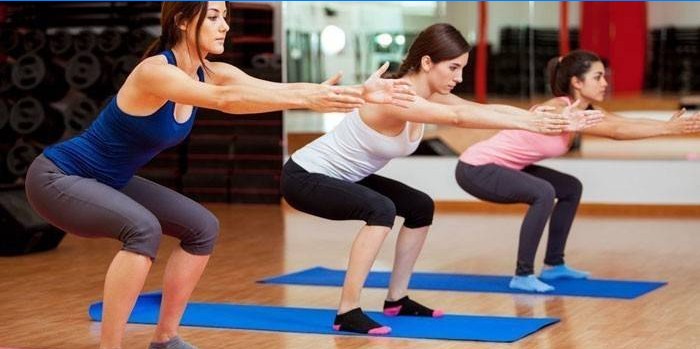 Les filles effectuent des squats classiques dans la salle de gym