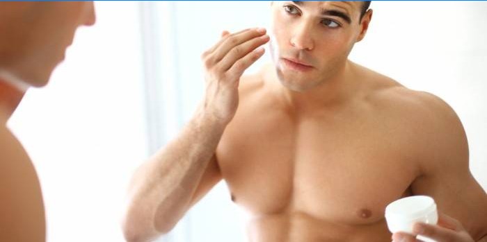 Un homme applique de la crème sur son visage