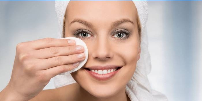 Fille essuie son visage avec tonique