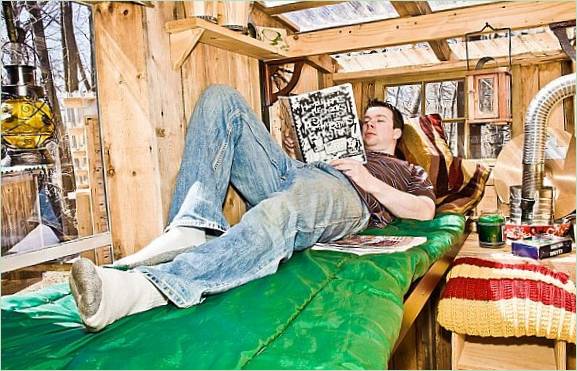Un homme est allongé sur un lit dans une cabane en bois