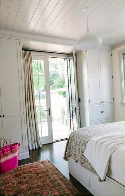 Une porte vitrée dans la chambre donne sur le jardin et le patio
