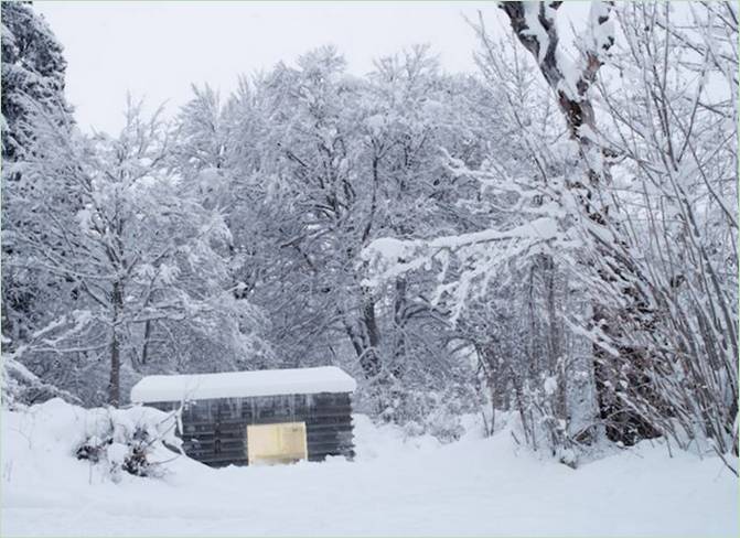 Maison avec cheminée dans la forêt enneigée