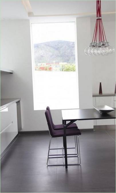 Chaises violettes et table à manger noire dans une cuisine blanche