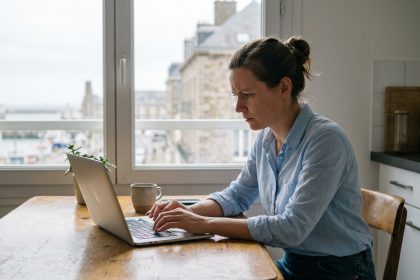Femme concentr&eacute;e travaillant sur son ordinateur dans un appartement moderne au Havre